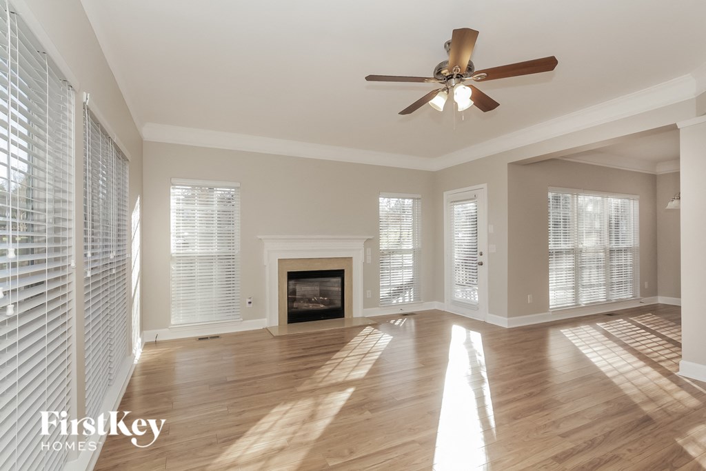 an empty living room with a ceiling fan and a fireplace