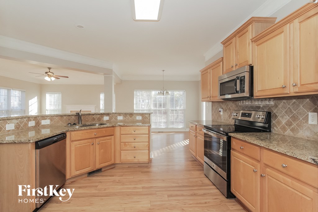 a large kitchen with wooden cabinets and granite counter tops and black appliances
