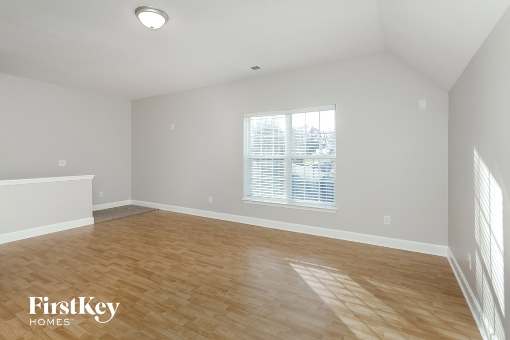 the spacious living room with hardwood flooring and a window