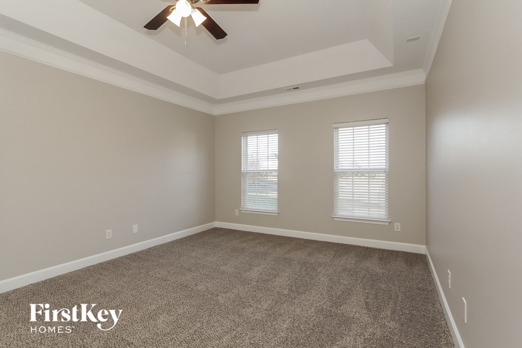 a empty room with a ceiling fan and two windows