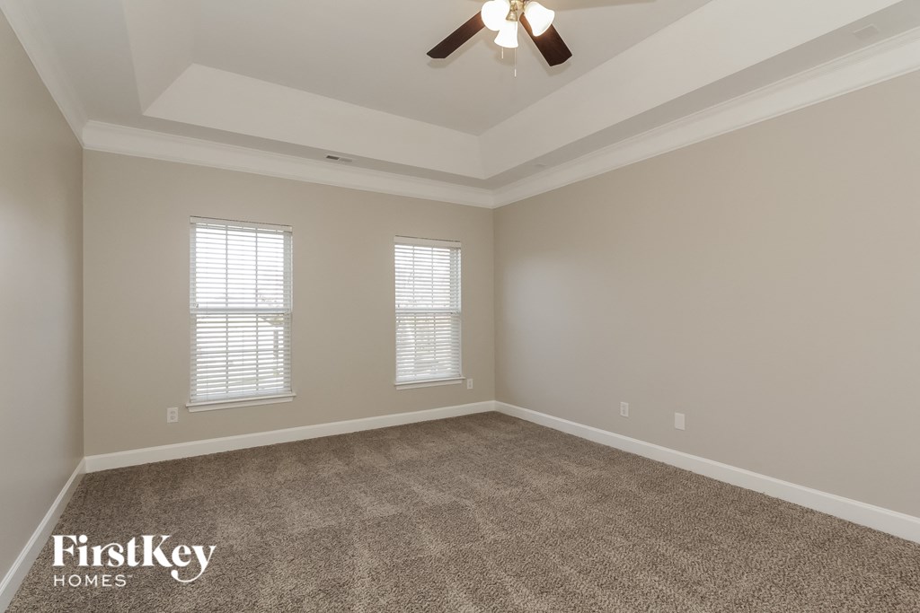 an empty living room with a ceiling fan and two windows