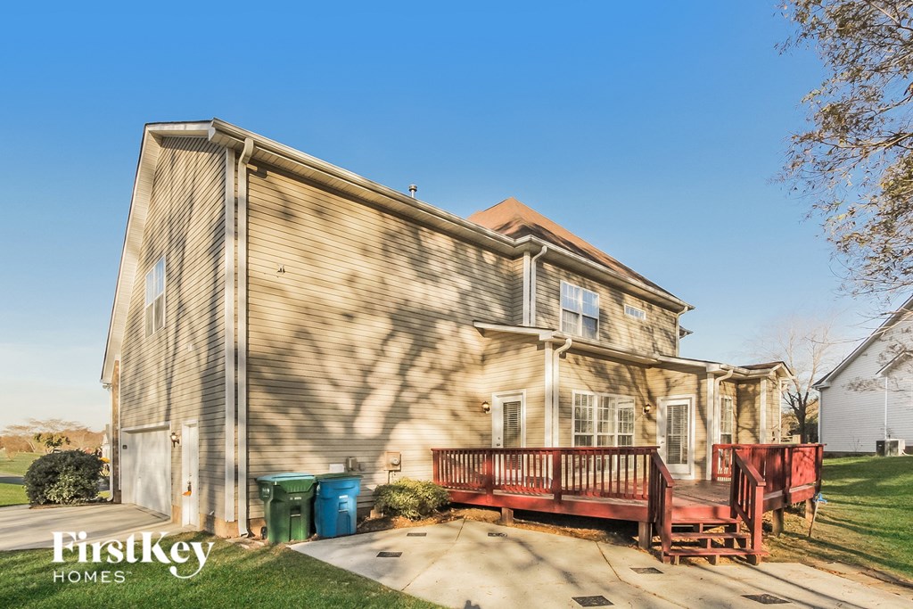 the exterior of a house with a wooden deck and trash cans