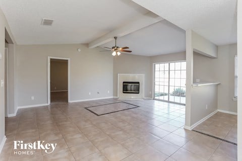 A spacious living room with a fireplace and a ceiling fan.