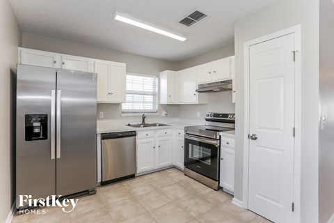 A kitchen with a refrigerator, sink, oven, and cabinets.