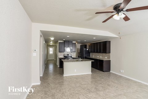 A spacious kitchen and living room with a ceiling fan.
