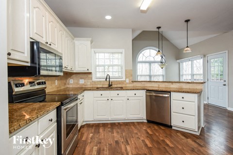A kitchen with white cabinets and a granite countertop.