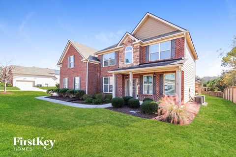 a red brick house with a yard and green grass