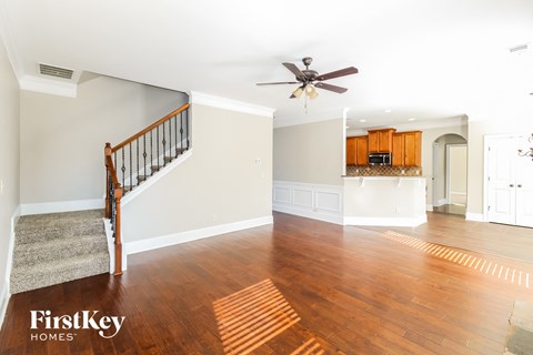 an empty living room with a ceiling fan and a kitchen