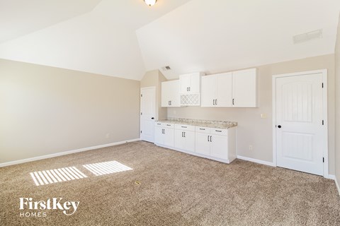 a white kitchen with white cabinets and white counters and a carpeted floor