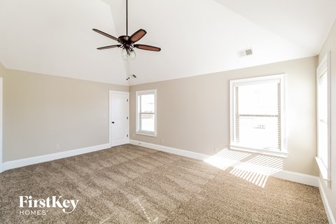 a carpeted living room with a ceiling fan and a window