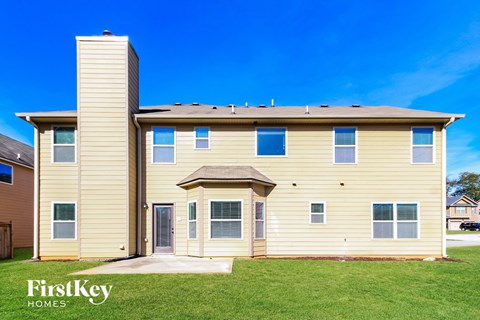 side view of a yellow house with white siding and green grass