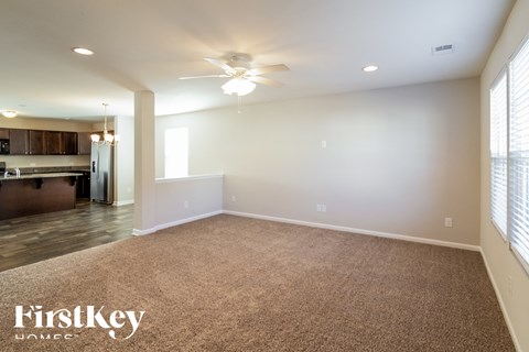 A spacious room with a carpeted floor and a ceiling fan.