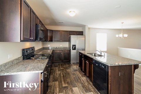 A kitchen with dark wood cabinets and a granite countertop.