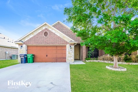 A house with a garage and a tree in front.