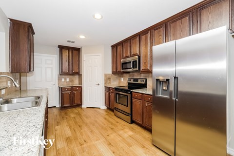 A kitchen with a stainless steel refrigerator and wooden cabinets.