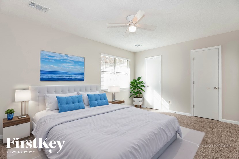 A bedroom with a large bed and a painting of a beach on the wall.