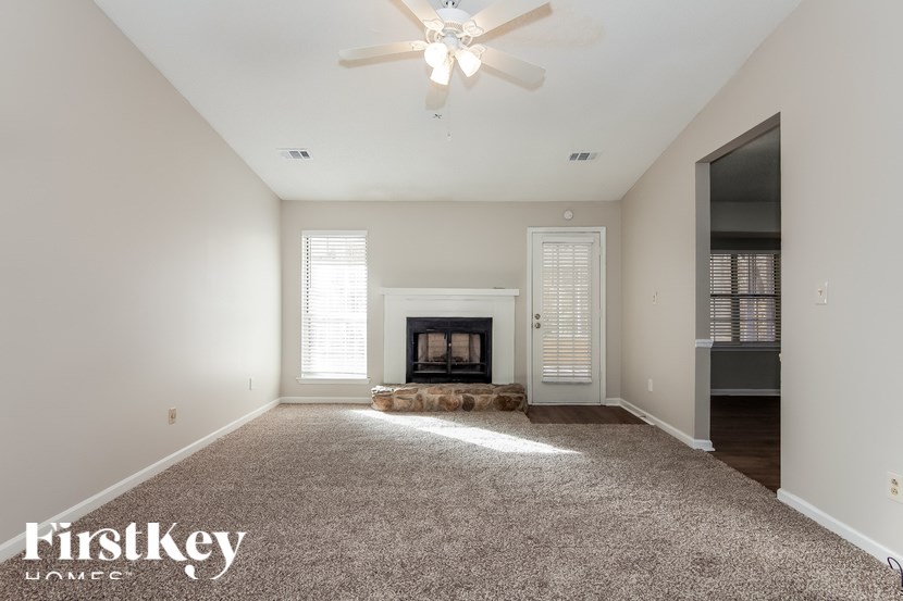 A spacious room with a fireplace and a ceiling fan.
