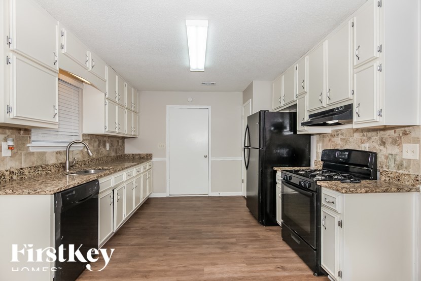 A kitchen with white cabinets and black appliances.