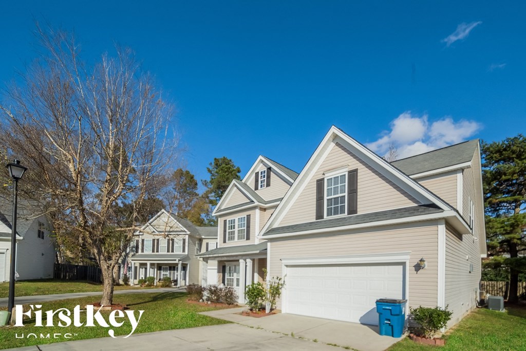 A large house with a garage and a blue bin in front.