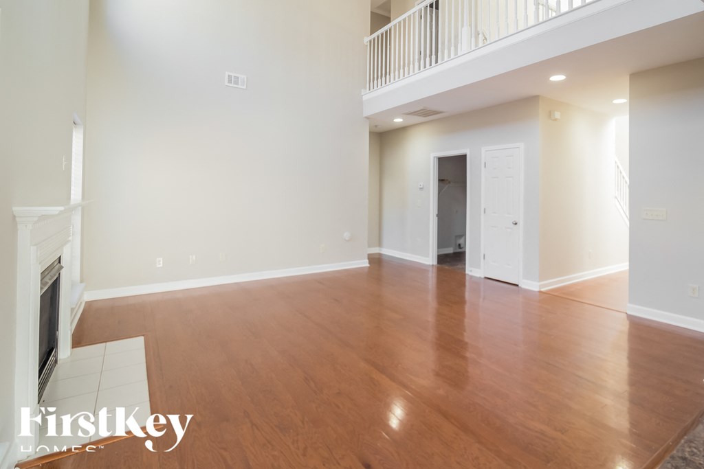 A large empty room with wooden floors and a fireplace.