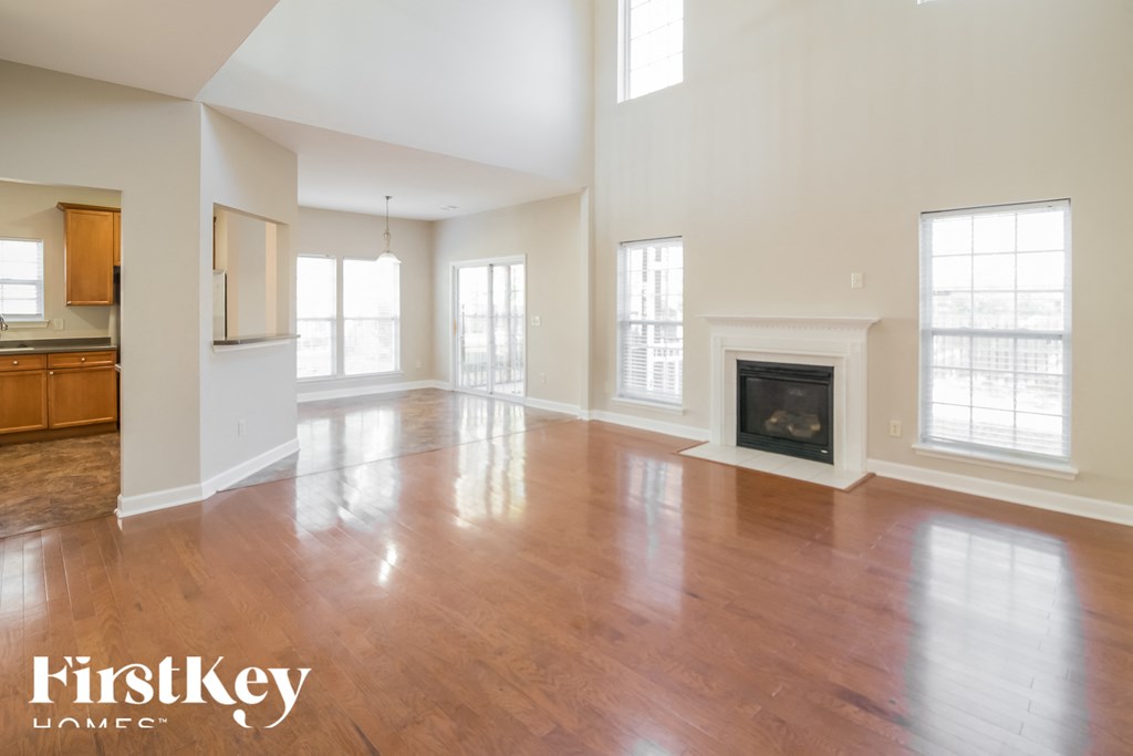 A large empty room with wooden floors and a fireplace.