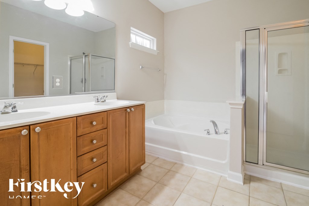 A bathroom with a tub, sink, and mirror.