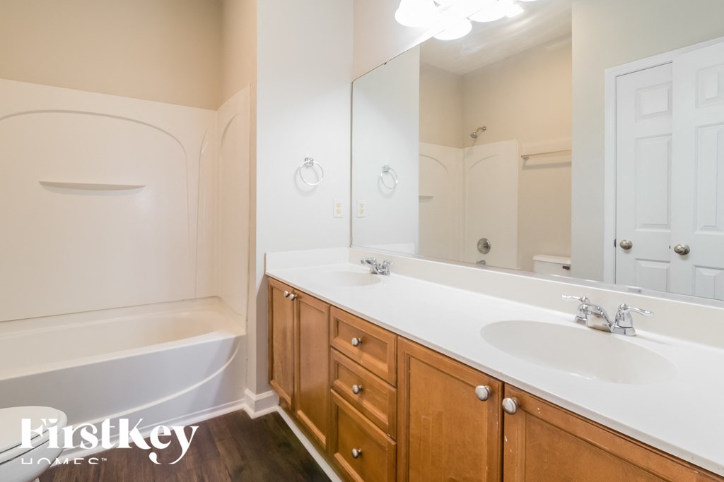 A bathroom with a white tub, sink, and wooden cabinets.