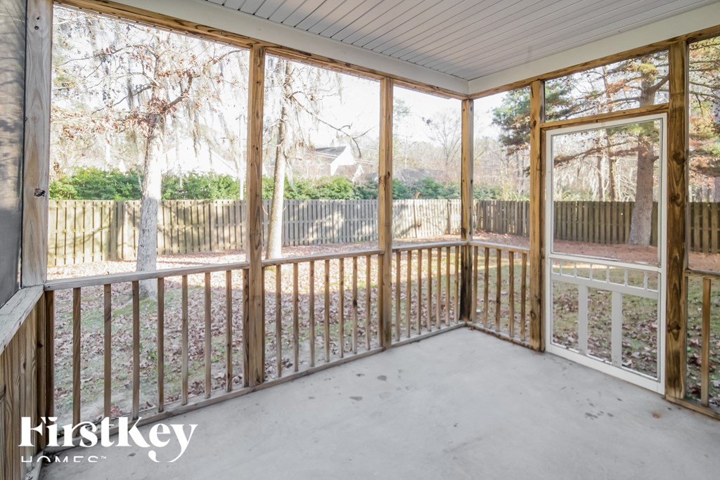 A sunny day in a room with a view of a fence and trees.