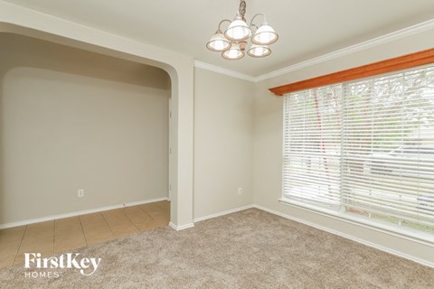 a dining room with a large window and a beige carpet