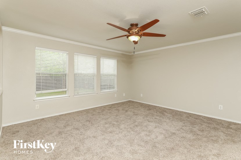 an empty bedroom with a ceiling fan and a window