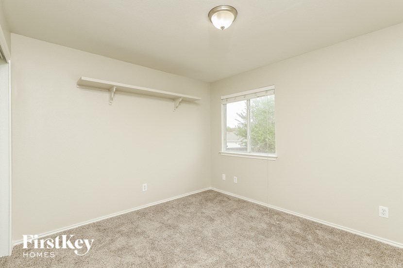 an empty bedroom with a window and a carpeted floor