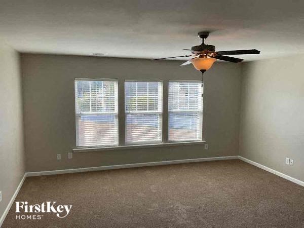 an empty room with a ceiling fan and three windows