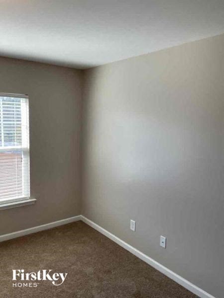 an empty room with a window and a brown carpet