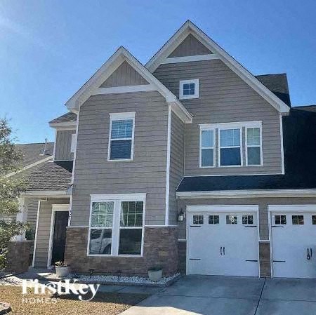 a brown house with two white garage doors