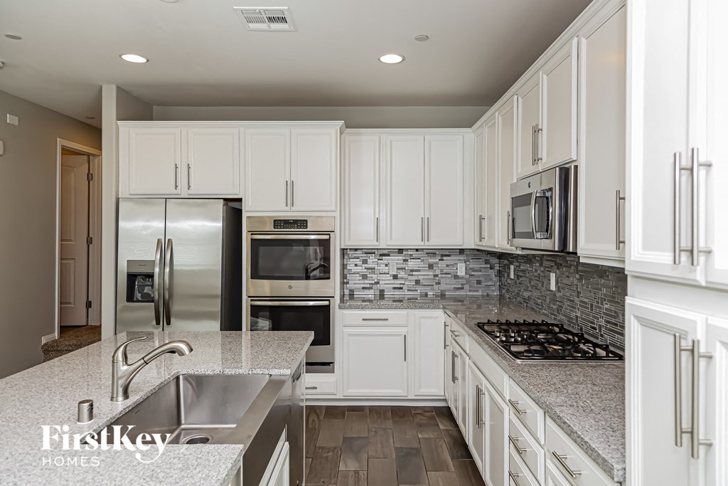 A kitchen with white cabinets and a stone backsplash.