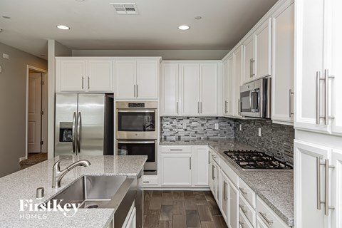 A kitchen with white cabinets and a stone backsplash.