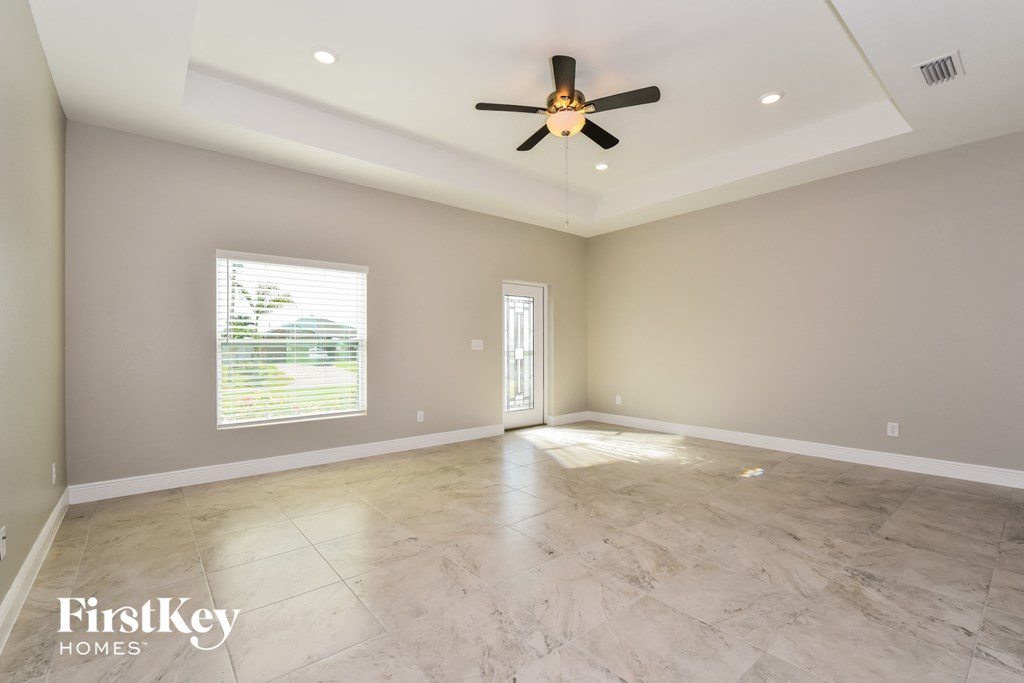 A spacious room with a ceiling fan and a window with blinds.