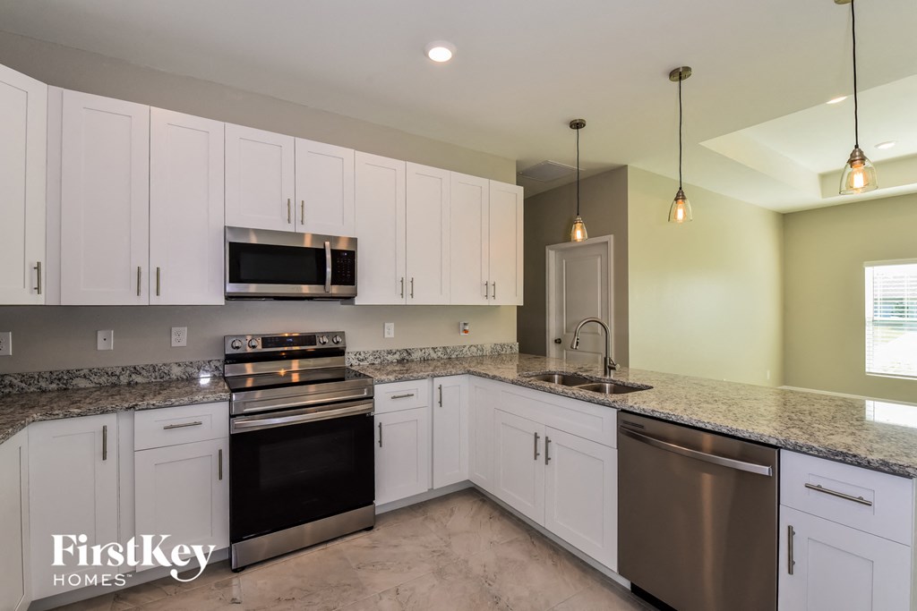 A kitchen with white cabinets and a granite countertop.