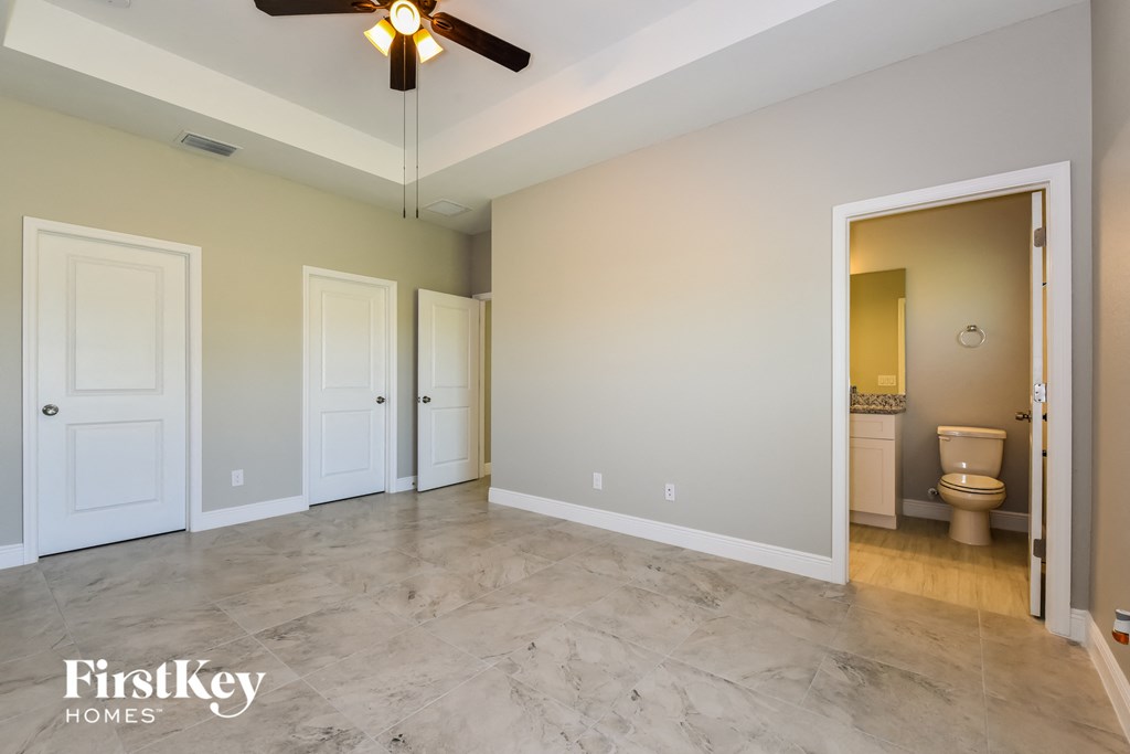 A spacious room with a ceiling fan and a bathroom visible through an open door.