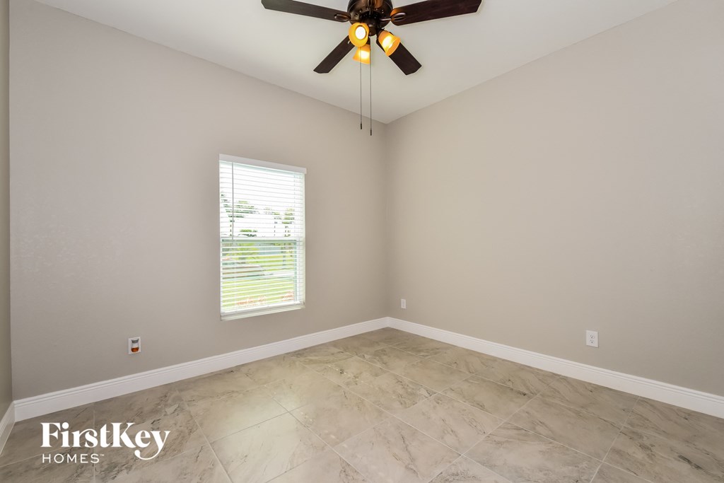 A room with a ceiling fan and a window with blinds.