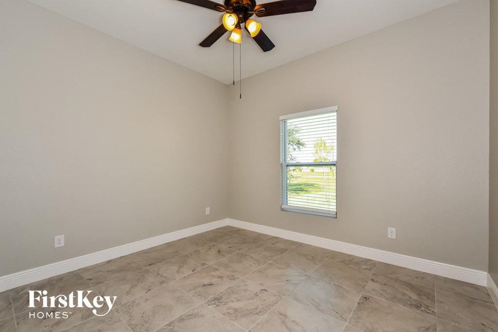 A room with a ceiling fan and a window letting in light.