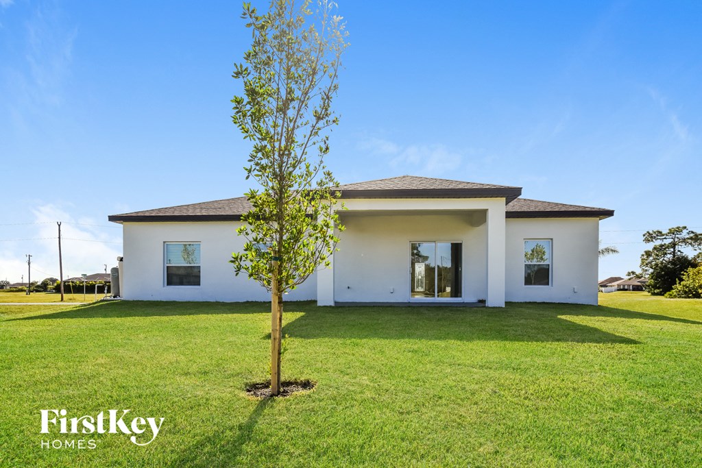 A white house with a tree in front of it.