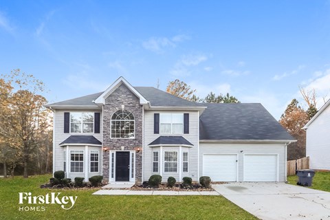 a white house with a gray roof and white garage doors