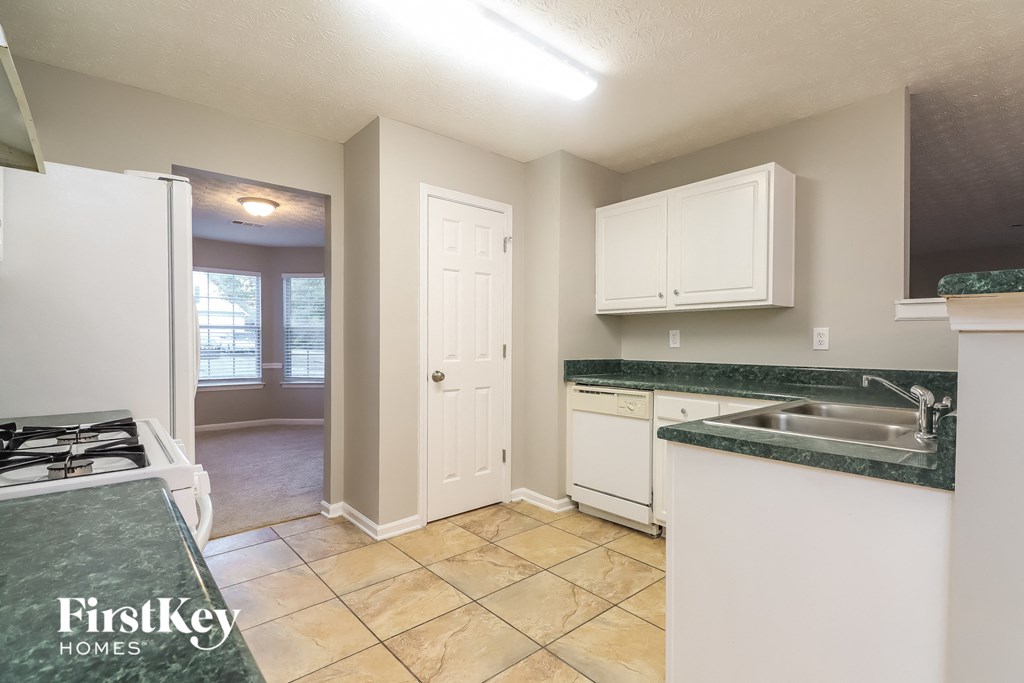 a kitchen with white cabinets and a sink and a stove