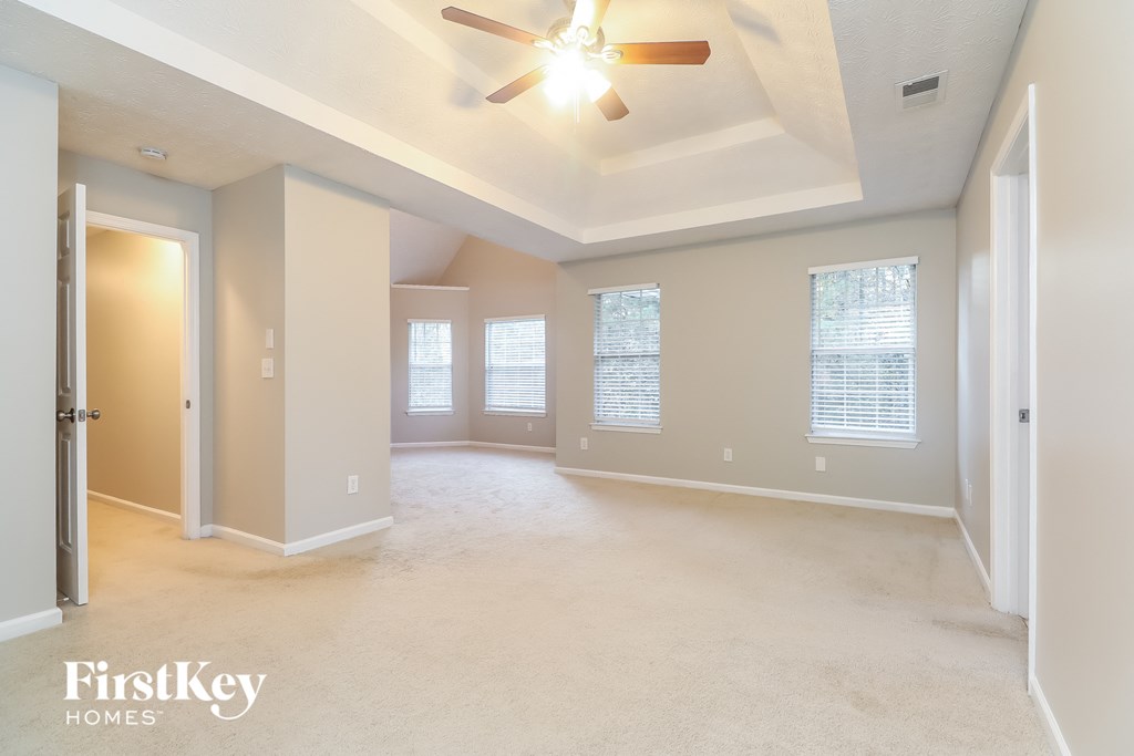 an empty living room with a ceiling fan and windows