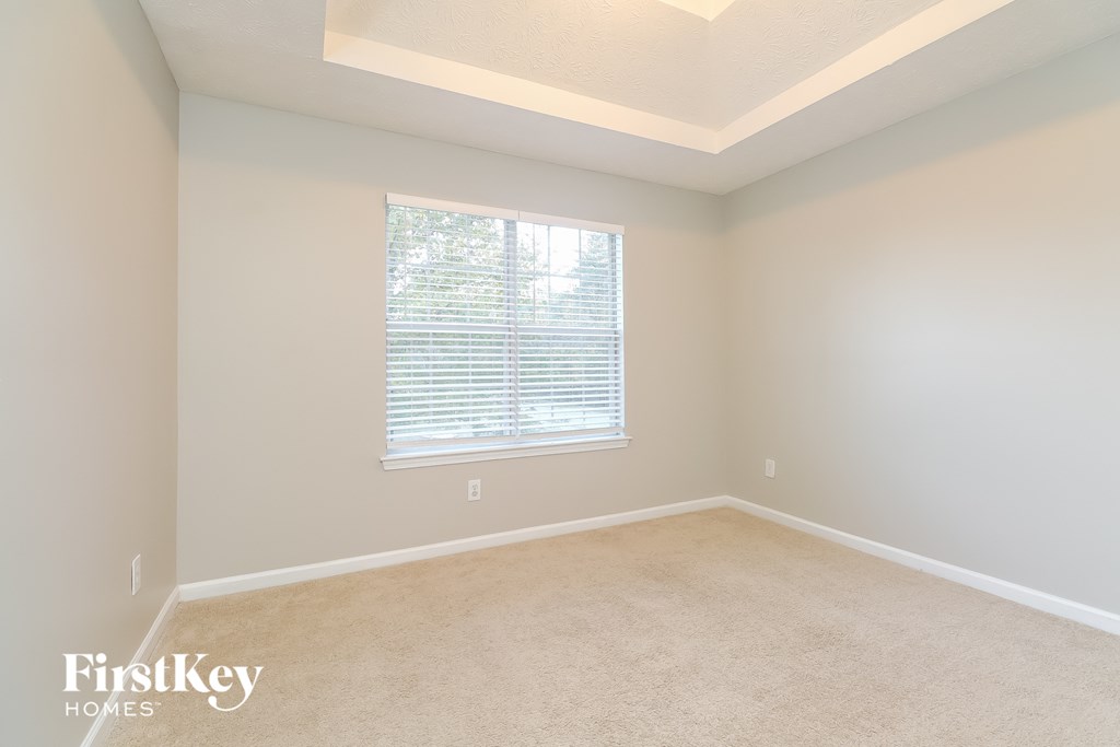 a bedroom with a large window and a carpeted floor