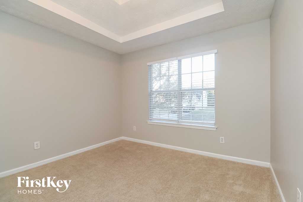 a bedroom with a large window and a carpeted floor