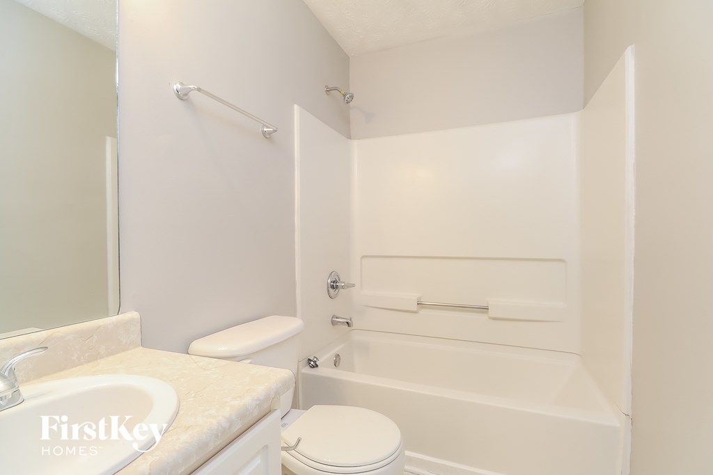 a white bathroom with a tub and a sink and a toilet