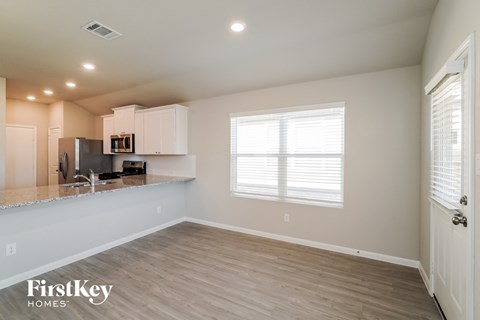 A spacious kitchen with white cabinets and a wooden floor.