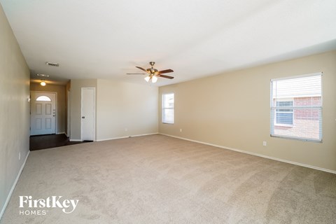 A spacious room with a ceiling fan and carpeted floor.